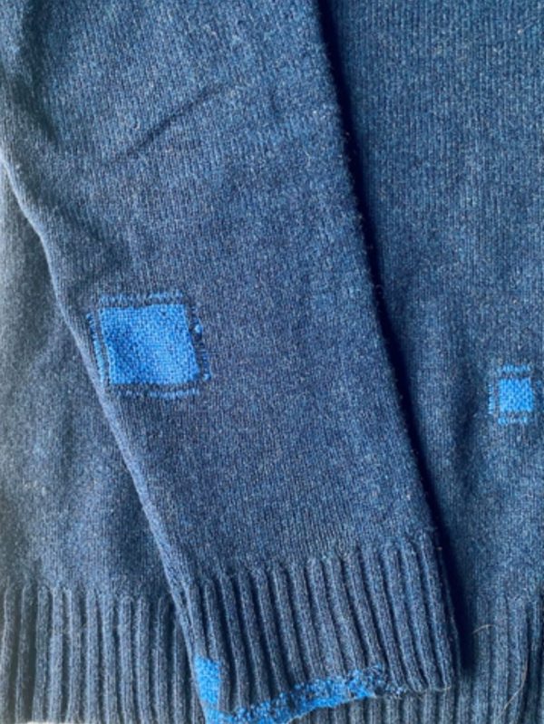 Light blue darned patches on a dark blue sweater.