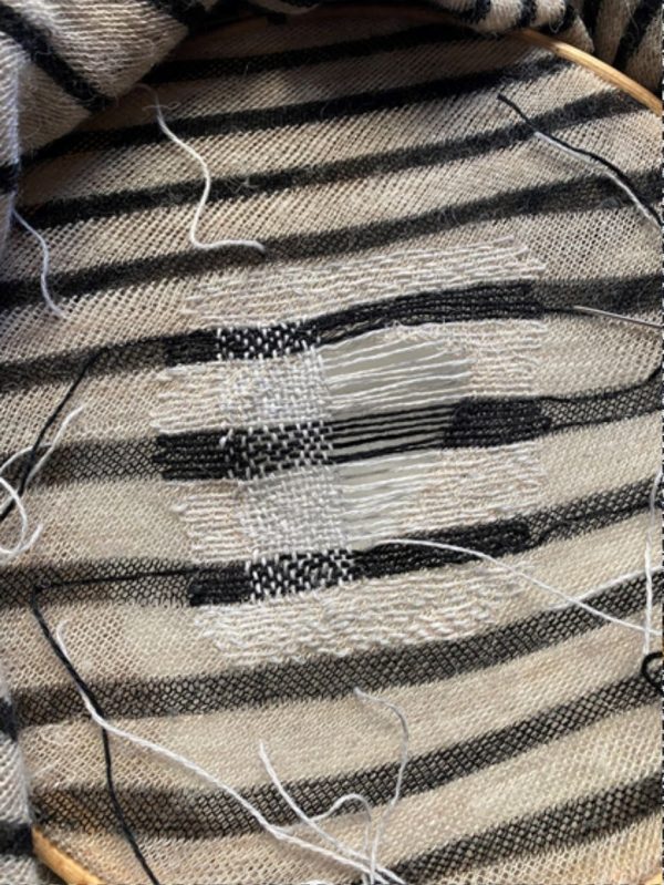 Mending a piece of knitwear with black and white stripes