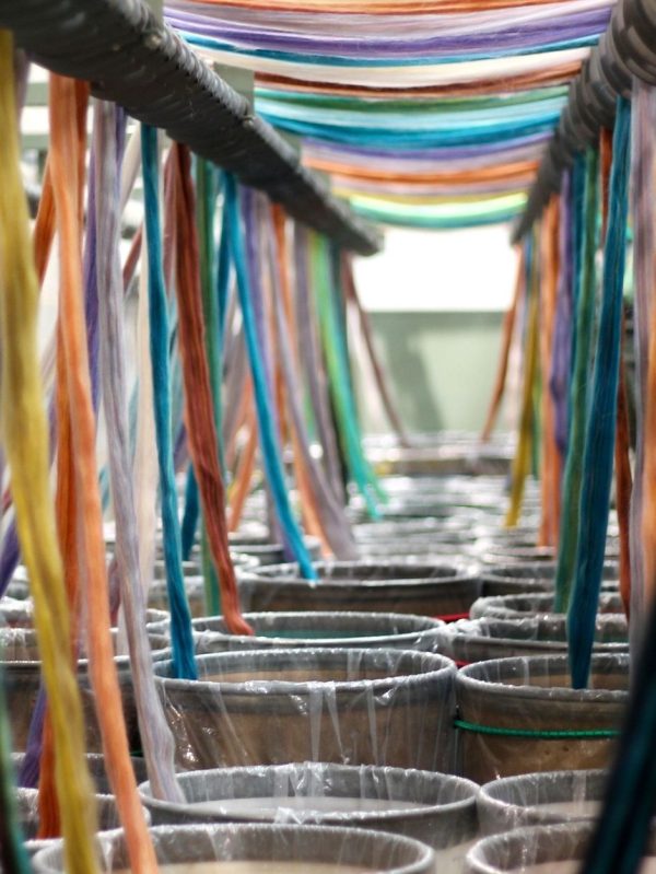 A rainbow of tops being fed from their cans into Kevin, one of our spinning machines.